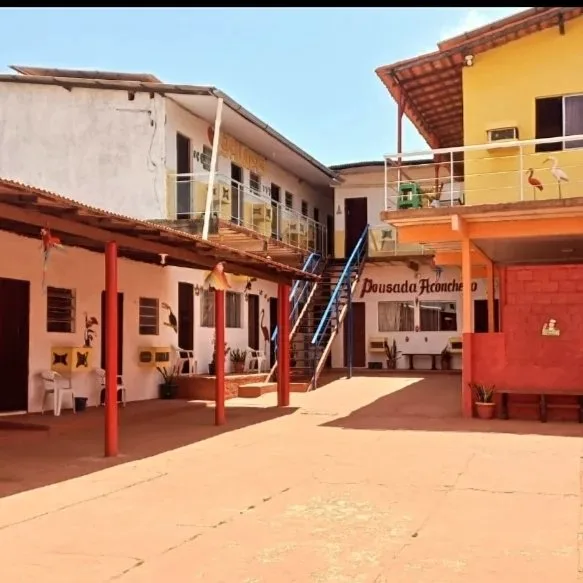 Pátio central da Pousada Aconchego, com os quartos ao redor, escada azul e pilares vermelhos